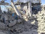 People stand on a pile of rubble that used to be the Huqah health facility 